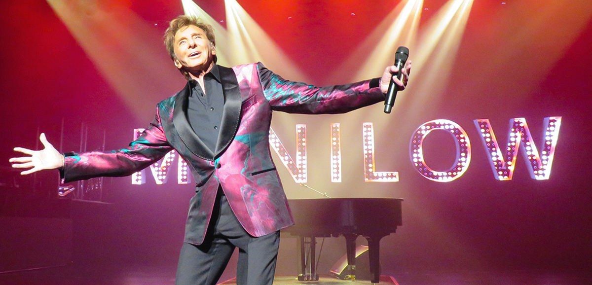 Barry Manilow on stage with his arms stretched out.